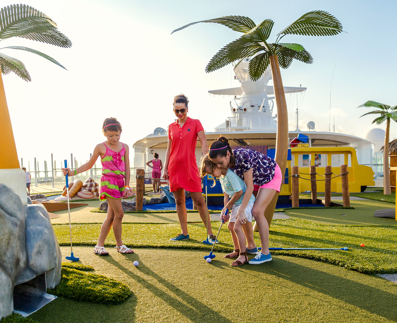 Family enjoying afternoon playing mini golf