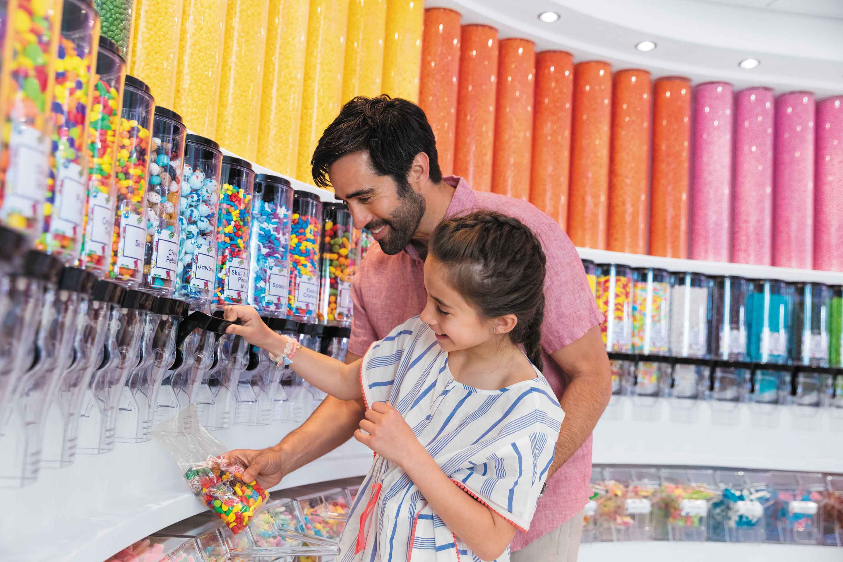 Father and daughter pouring bags of candy at the candy store onboard, Sugar Beach